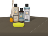 Retique It Black Walnut Kit with Matte Tripletique, Light Wood Wood'n Primer, Black Walnut Gel Stain Alternative, paintbrush, and yellow sponge on a tabletop.