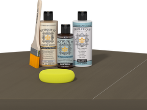 Retique It Black Walnut Kit with Matte Tripletique, Light Wood Wood'n Primer, Black Walnut Gel Stain Alternative, paintbrush, and yellow sponge on a tabletop.