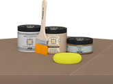 Retique It Barn Wood Kit with Matte Polytique It, Light Wood Wood'n Primer, Barn Wood Gel Stain Alternative, paintbrush, and yellow sponge on a tabletop.