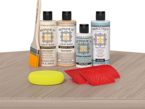 Retique It® Wood'n Finish Kit Sun Bleached tabletop with wood finish products and application tools on a surface.