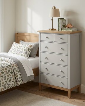 Gray dresser with wooden top next to a bed with patterned bedding.