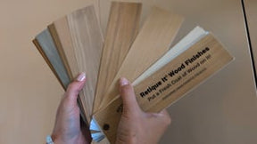 Hands fanning out wood finish sample boards showing different Retique It wood finish colors and textures.